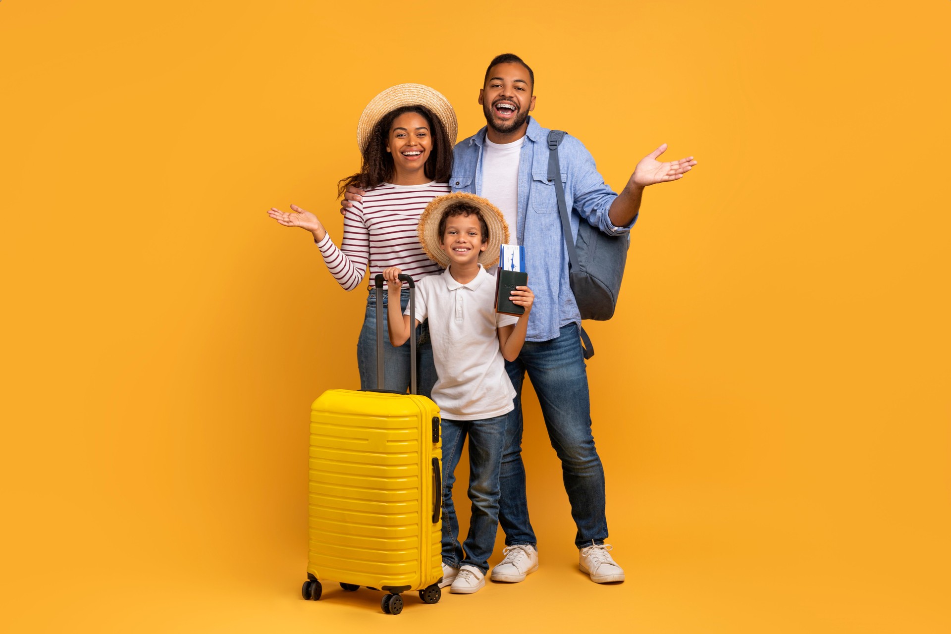 Portrait of excited black family of three with suitcase and travel tickets